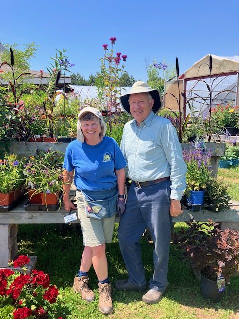 Anne and John Keuper of Island Pride Garden Co post in front of their plants and greenhouses.